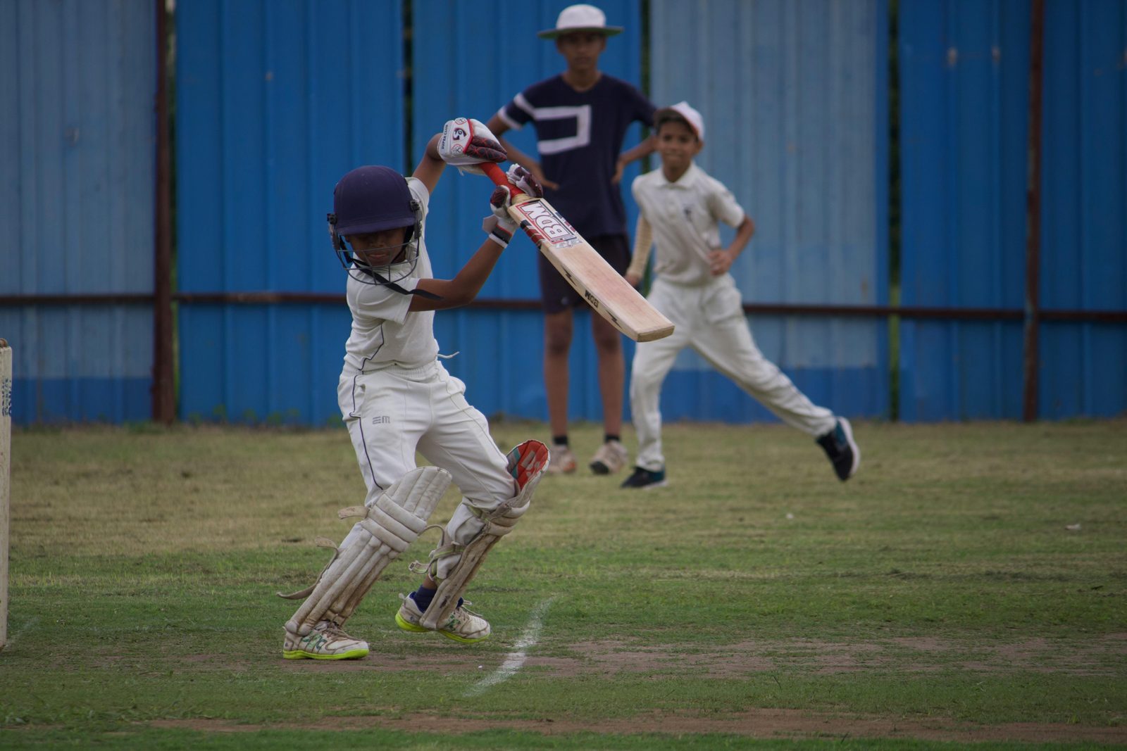Children playing cricket on a green outdoor field